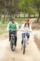 Couple riding bicycle in park