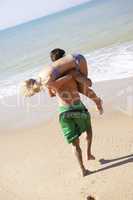 Young couple play on beach