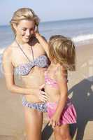 Mother playing with young girl on beach