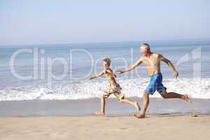 Grandfather chasing young boy on beach