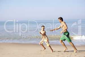 Father chasing young boy on beach