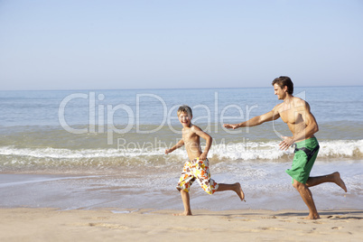 Father chasing young boy on beach