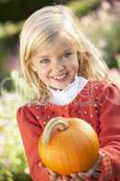 Young girl posing with pumpkin in garden