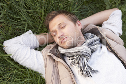 Young man napping alone on grass