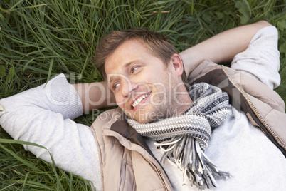 Young man lying alone on grass