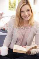 Woman drinks while reading book