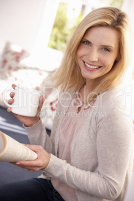 Woman drinks while reading book