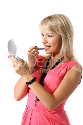 Beautiful young girl looks into the mirror and lipstick