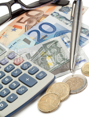 Cash, coins, pen, glasses and pocket calculator