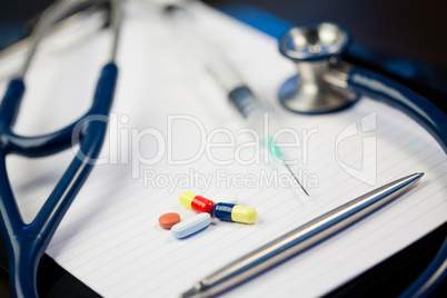 Note pad with stethoscope and pen along with  serynge and capsul