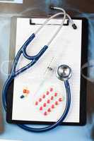 Note pad and blister strip with pills and blue stethoscope