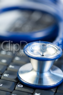 Blue stethoscope in the middle of keyboard