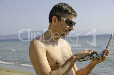 Man relaxing on the Beach with his Notebook