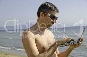 Man relaxing on the Beach with his Notebook