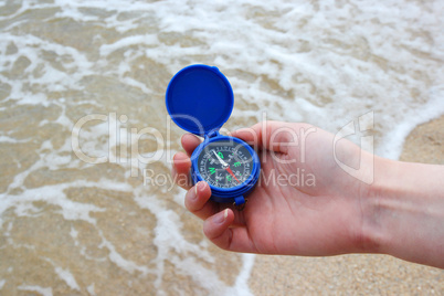 Dark blue compass in hands on the background a sea