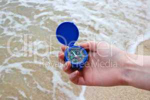 Dark blue compass in hands on the background a sea
