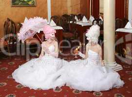 Two girls in wedding dresses and masks