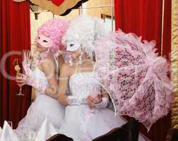Two girls in wedding dresses and masks