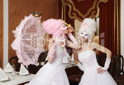 Two girls in wedding dresses and masks