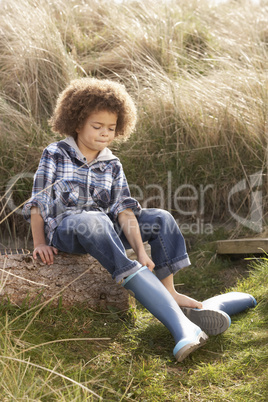 Young Boy Putting On Wellington Boots