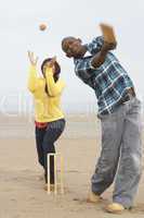 Young Couple Playing Cricket On Autumn Beach Holiday