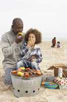 Young Family Enjoying Barbeque On Beach