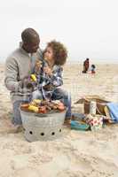 Young Family Enjoying Barbeque On Beach