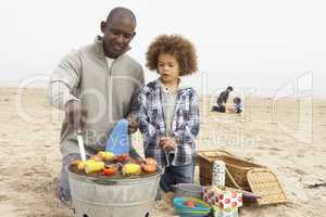 Young Family Enjoying Barbeque On Beach