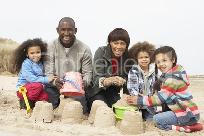 Young Family Building Sandcastle On Beach Holiday