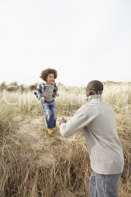 Father And Son Having Fun In Sand Dunes