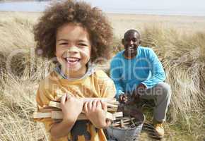 Father And Son Collecting Firewood On Beach Camping Holiday