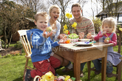 Family Decorating Easter Eggs On Table Outdoors