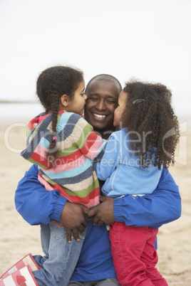 Father And Daughters Relaxing On Winter Beach Break