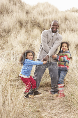 Father And Daughters Having Fun In Sand Dunes