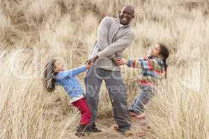 Father And Daughters Having Fun In Sand Dunes