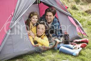 Young Family Relaxing Inside Tent On Camping Holiday