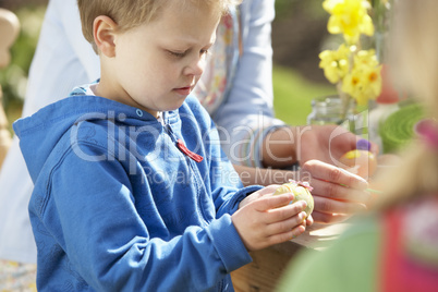 Mother And Children Decorating Easter Eggs On Table Outdoors