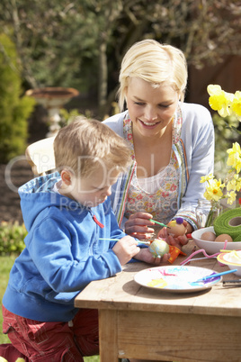 Mother And Son Decorating Easter Eggs On Table Outdoors