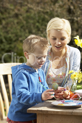 Mother And Son Decorating Easter Eggs On Table Outdoors