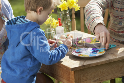 Father And Son Decorating Easter Eggs On Table Outdoors Father And Son Decorating Easter Eggs On Table Outdoors