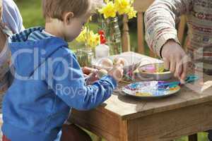 Father And Son Decorating Easter Eggs On Table Outdoors