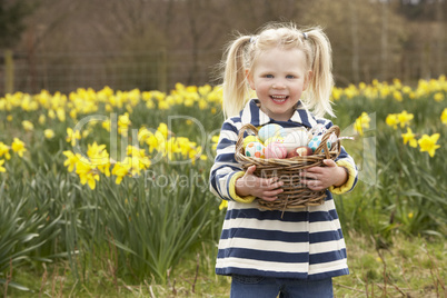 Young Girl Holding Basket Of Decorated Eggs In Daffodil Field