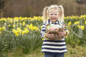 Young Girl Holding Basket Of Decorated Eggs In Daffodil Field
