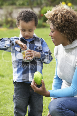 Mother Helping Son To Unwrap Chocolate Easter Egg