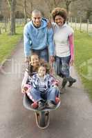 Family Having Ride In Wheelbarrow In Countryside