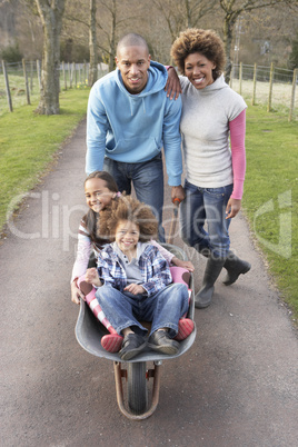 Family Having Ride In Wheelbarrow In Countryside
