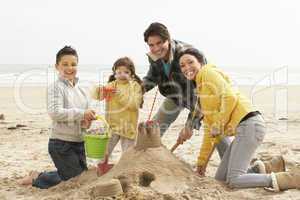 Family Building Sandcastle On Winter Beach