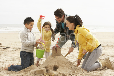 Family Building Sandcastle On Winter Beach