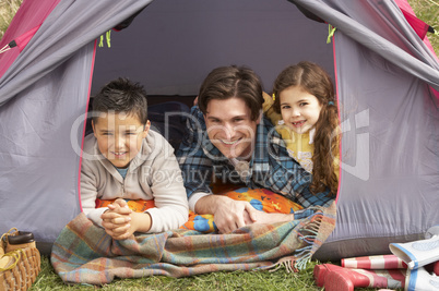 Young Family Relaxing Inside Tent On Camping Holiday