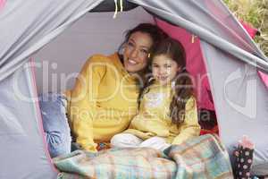 Mother And Daughter Relaxing Inside Tent On Camping Holiday